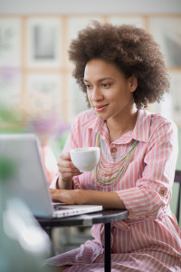 Charming mixed race woman in striped pink dress aitting in coffe